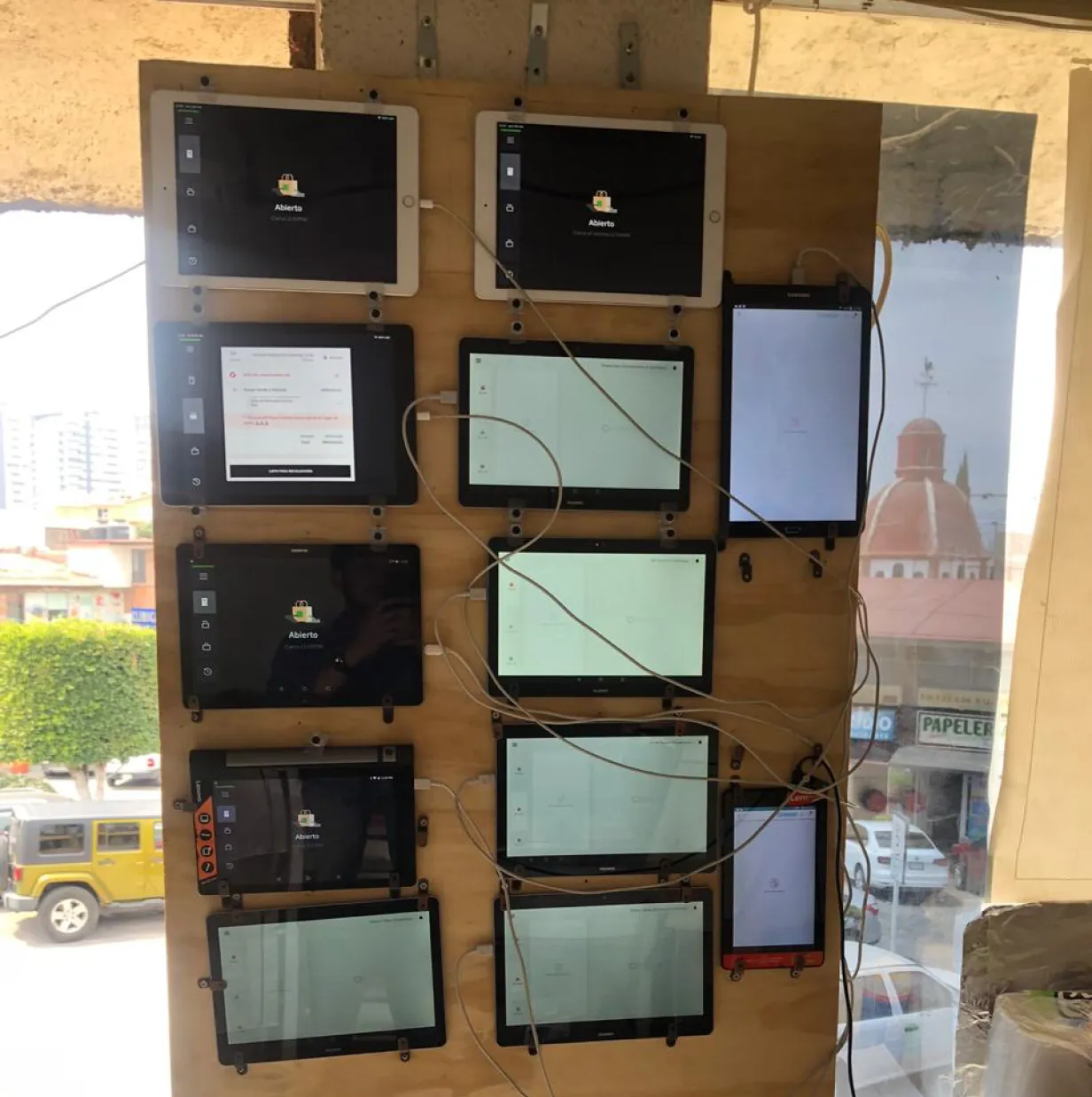Dark Kitchen field research 2019 — 10+ delivery-app tablets for Uber Eats, Didi Food, Rappi and iFood pinned to a wooden wall and wired chaotically, the operational pain mipOS set out to replace